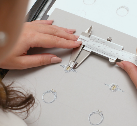 A woman is drawing a bespoke sapphire engagement ring sketch
