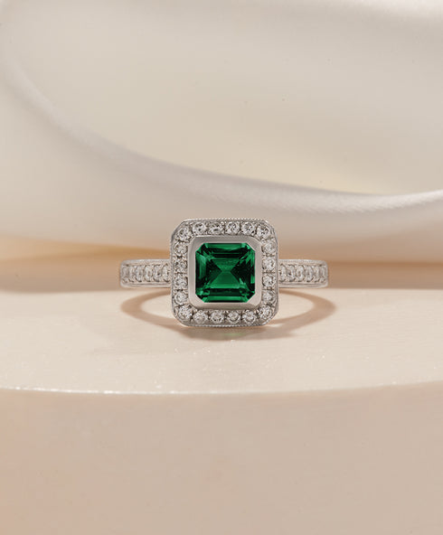 emerald engagement ring with square halo and diamond band