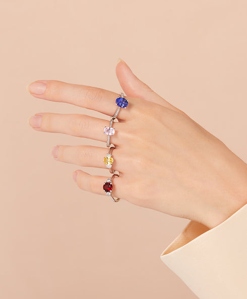 Four coloured sapphire engagement rings on a women's hand