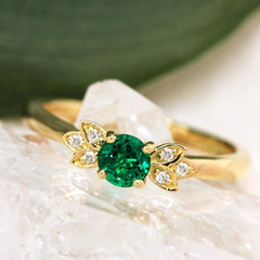 a emerald engagement ring in yellow gold with leafy diamonds on the shoulder