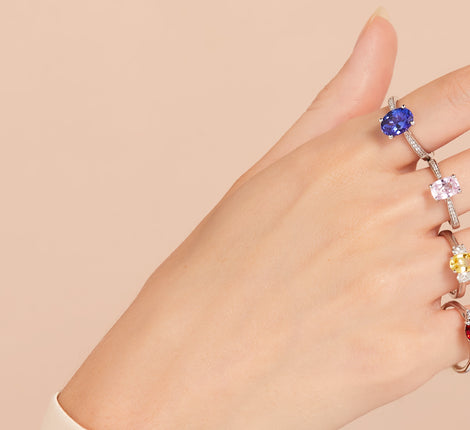 Four coloured sapphire engagement rings on a women's hand